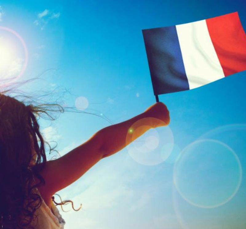 Des gens souriants participant à un bal populaire du 14 juillet avec des drapeaux français